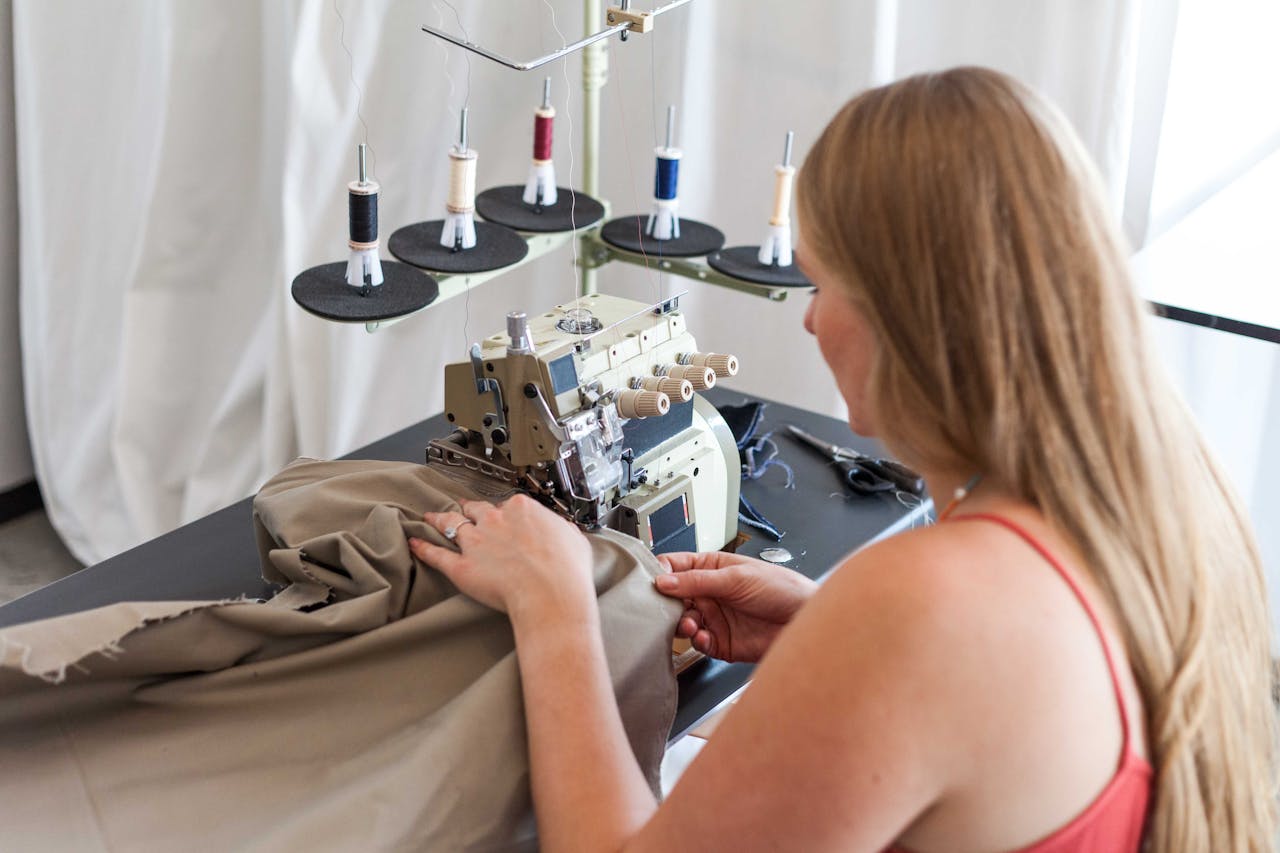 Services A woman sewing fabric using a sewing machine in a studio setting.