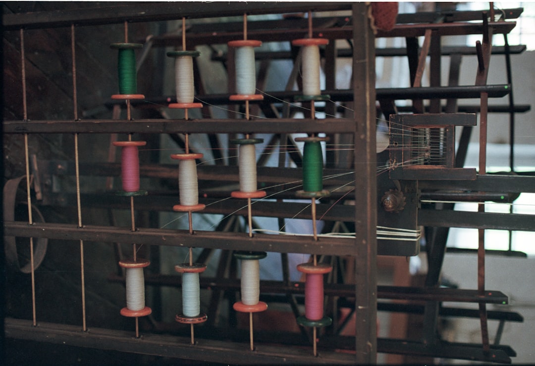 spools-of-colorful-thread-on-a-wooden-rack-ofwkugvnn40